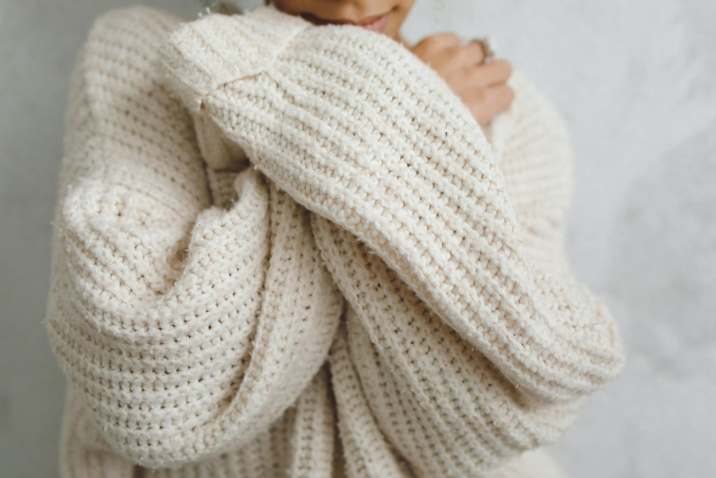 Person wrapped in a knitted blanket, symbolising the comfort and lasting support of a thoughtful bereavement gift.