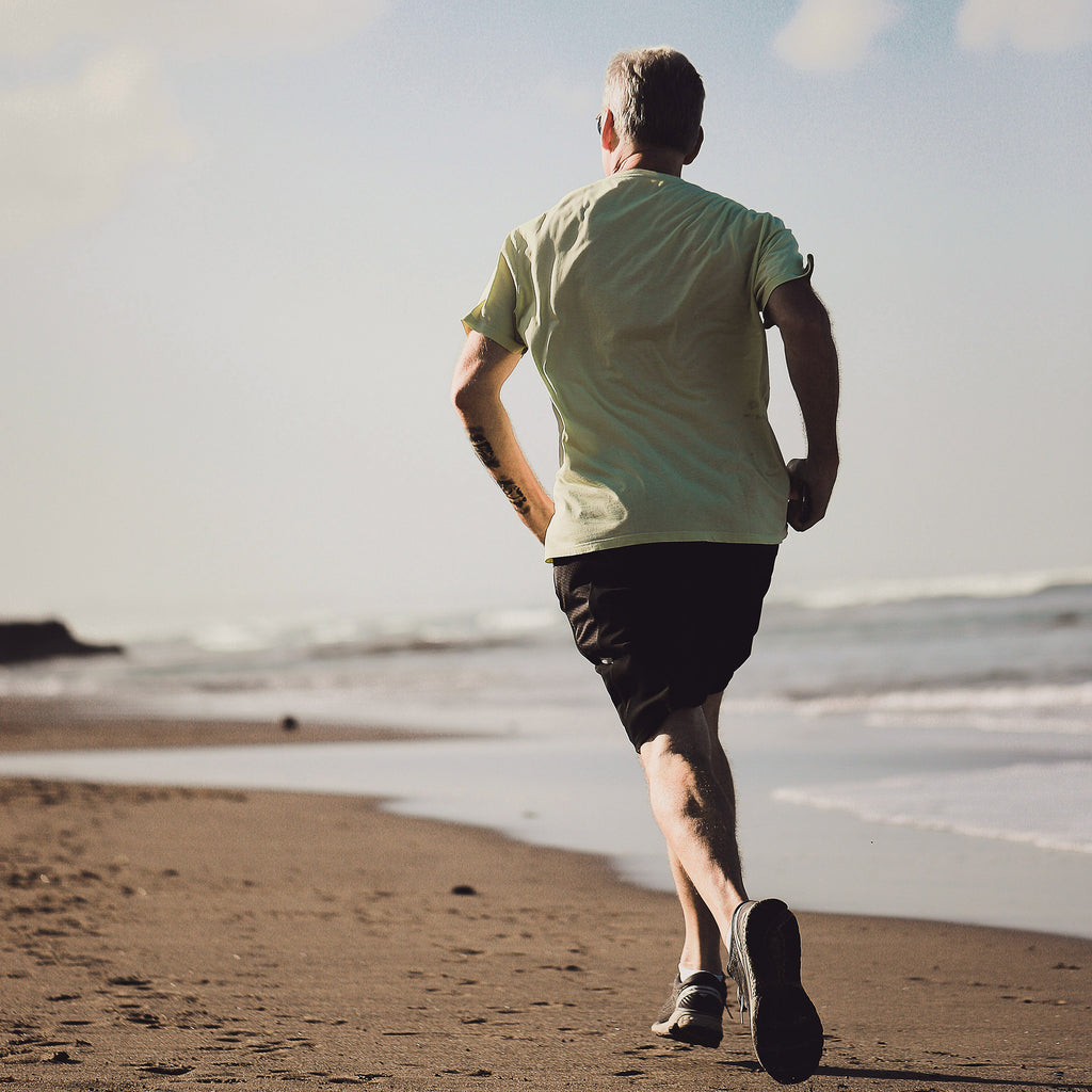 Person running along the beach to represent health, recovery and active living.