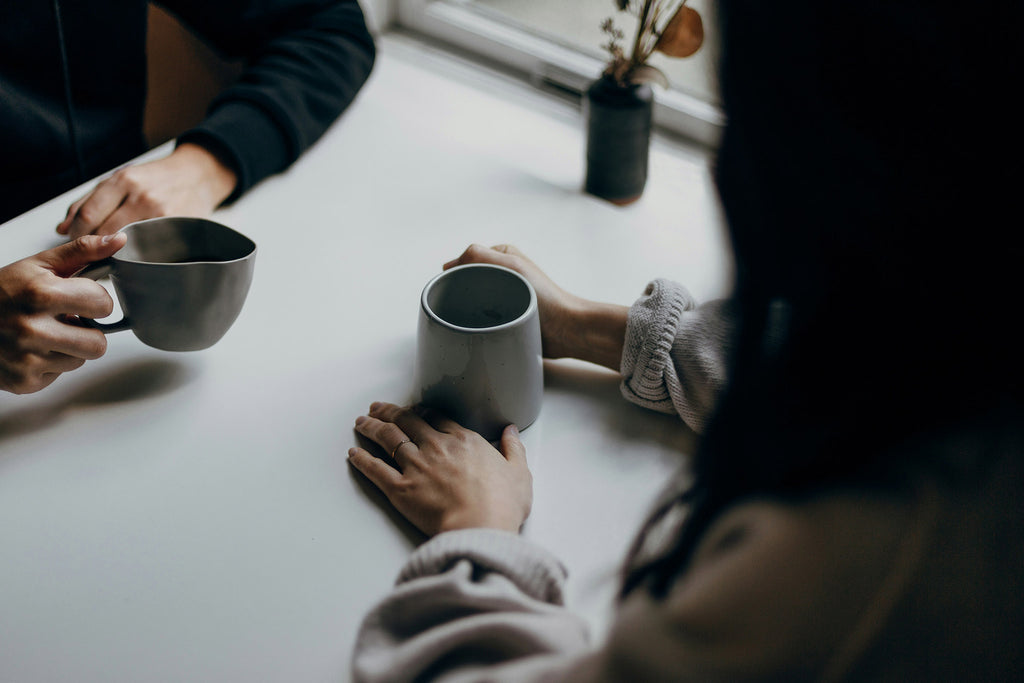 People sharing a conversation over coffee, representing connection, support and better mental health.