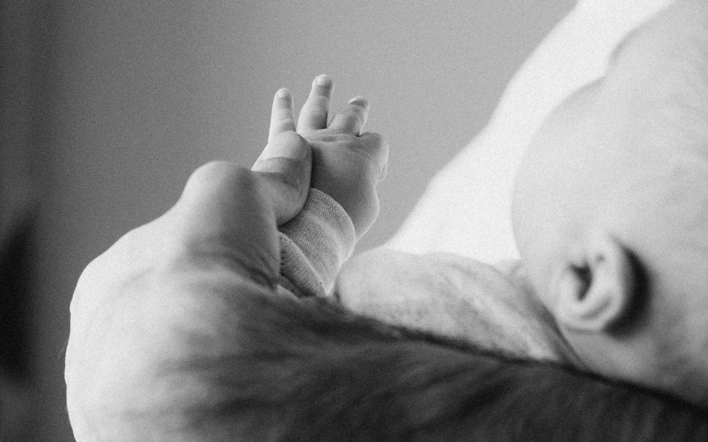 Baby reaching out while being held, representing the support provided by Cerebral Palsy Alliance.