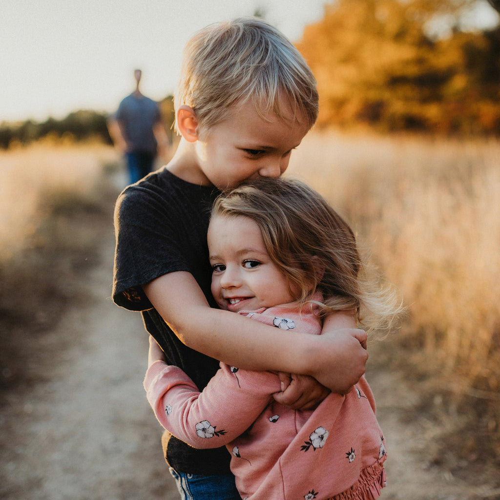 Young children hugging outdoors to represent protecting and supporting Australian children.