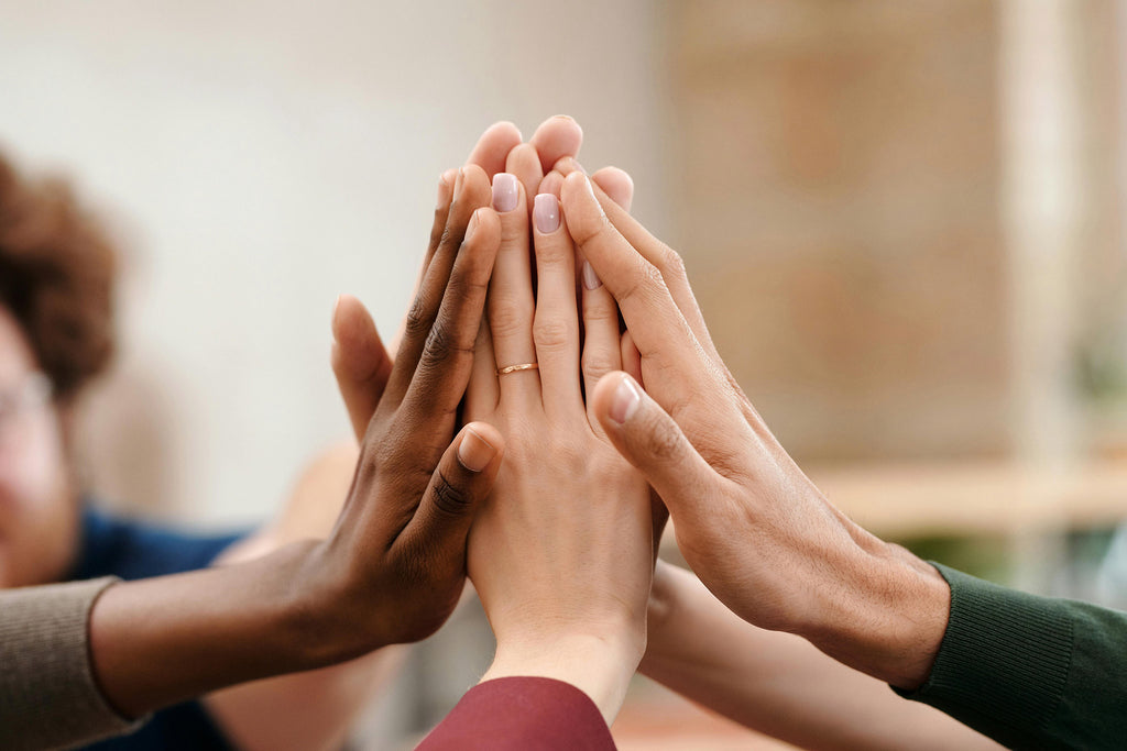 People placing their hands together, representing support, connection and community for people living with dementia and their families.