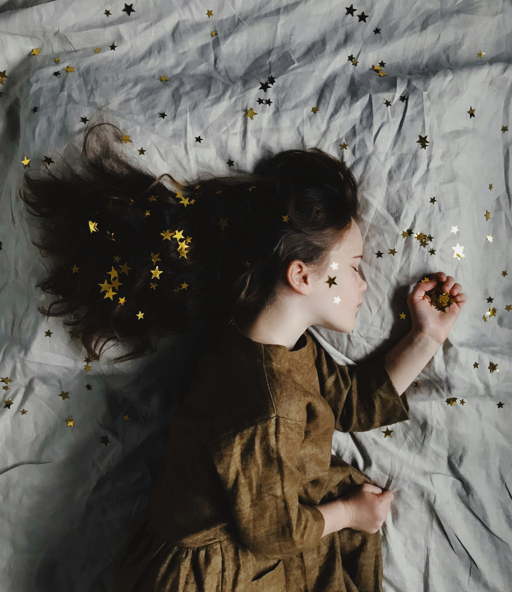 Young child resting among golden stars, representing hope, healing and support after the loss of a loved one.