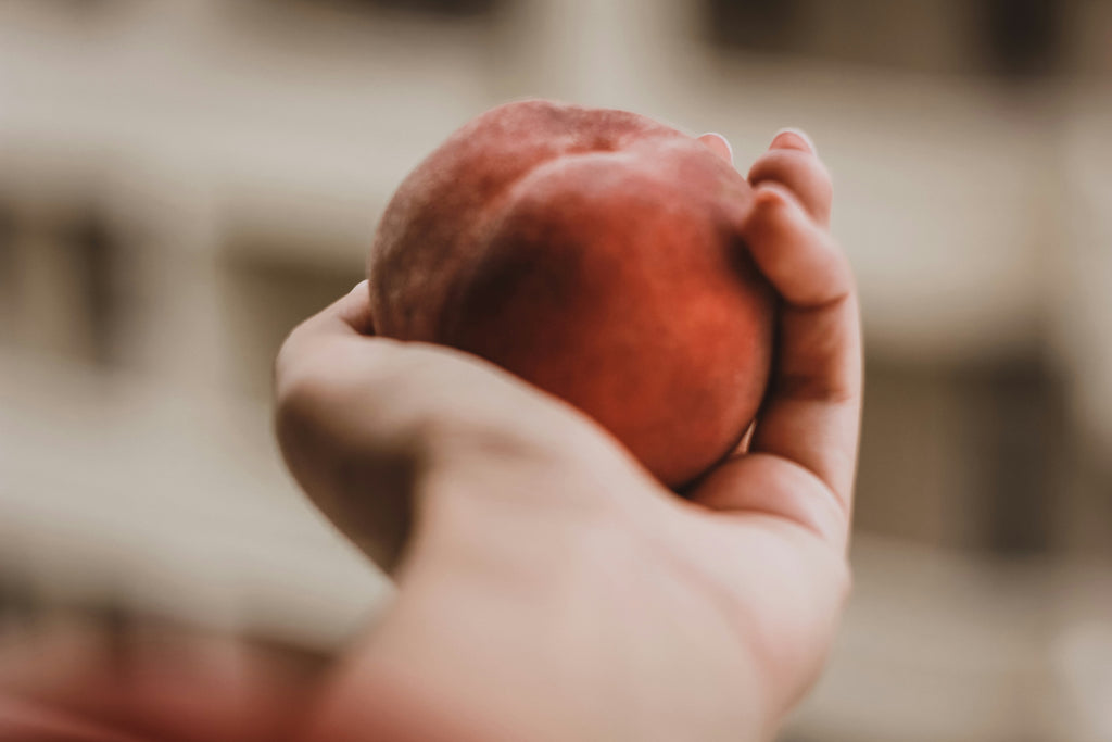 Fresh peach held in a hand, representing Foodbank Australia's mission to provide nutritious food to people in need.