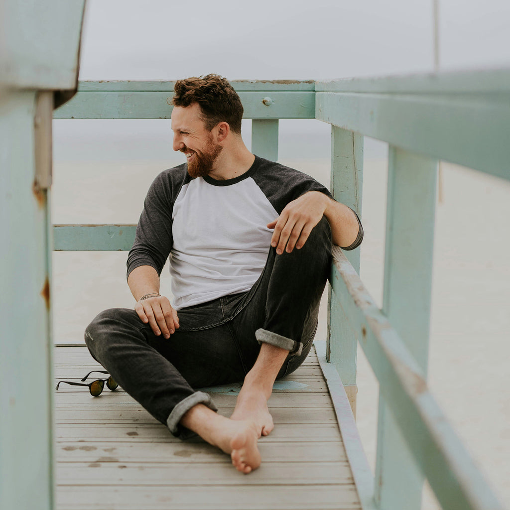 Man sitting outdoors smiling to represent men's mental health and wellbeing.