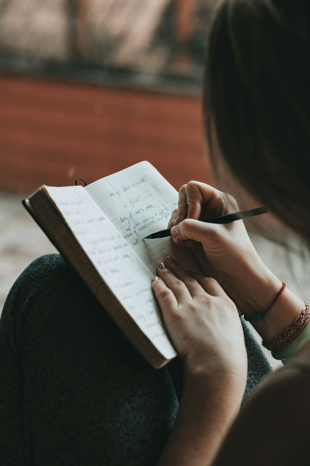 Person writing in a journal, representing reflection, wellbeing and mental health support.