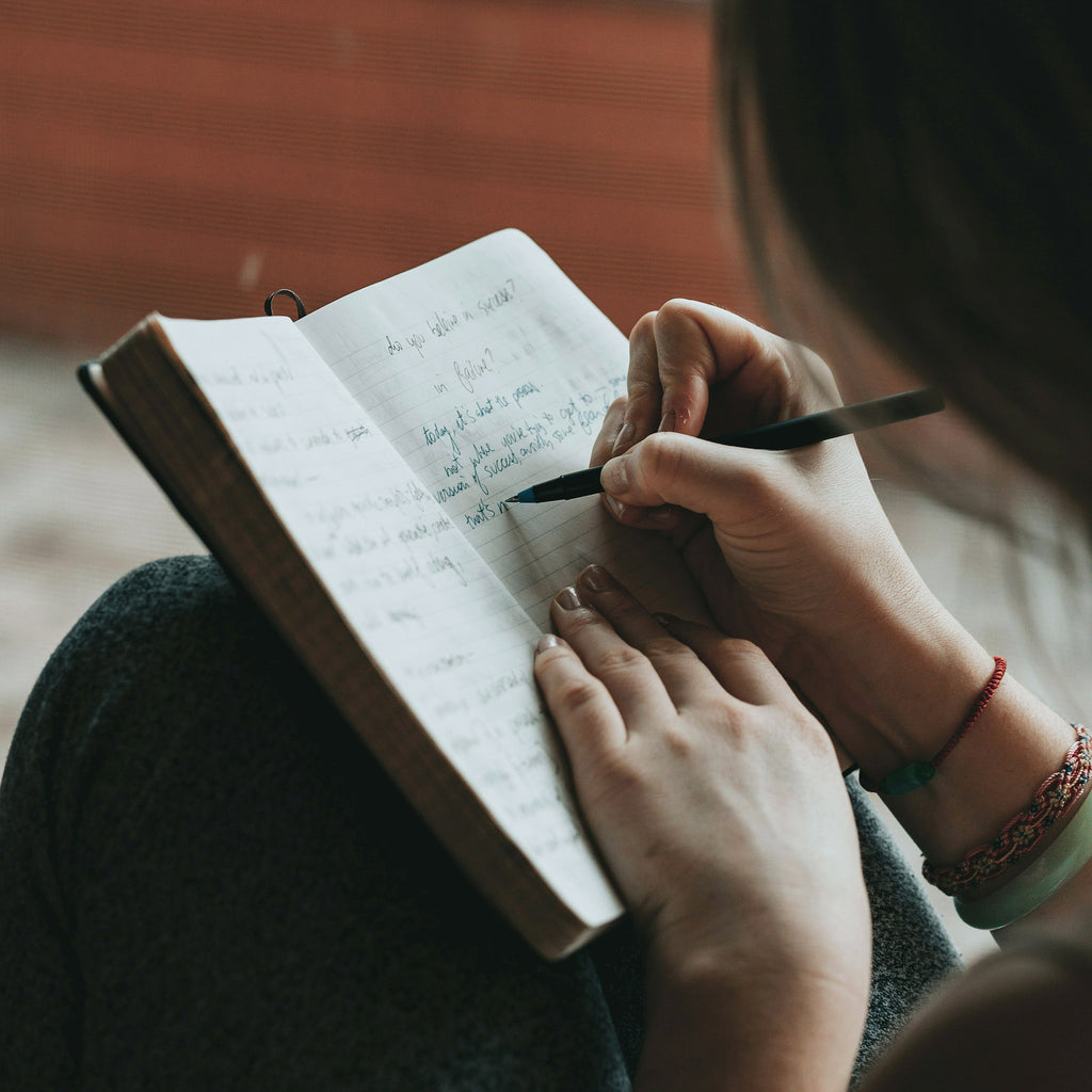 Person writing in a journal to represent mental health, reflection and support.