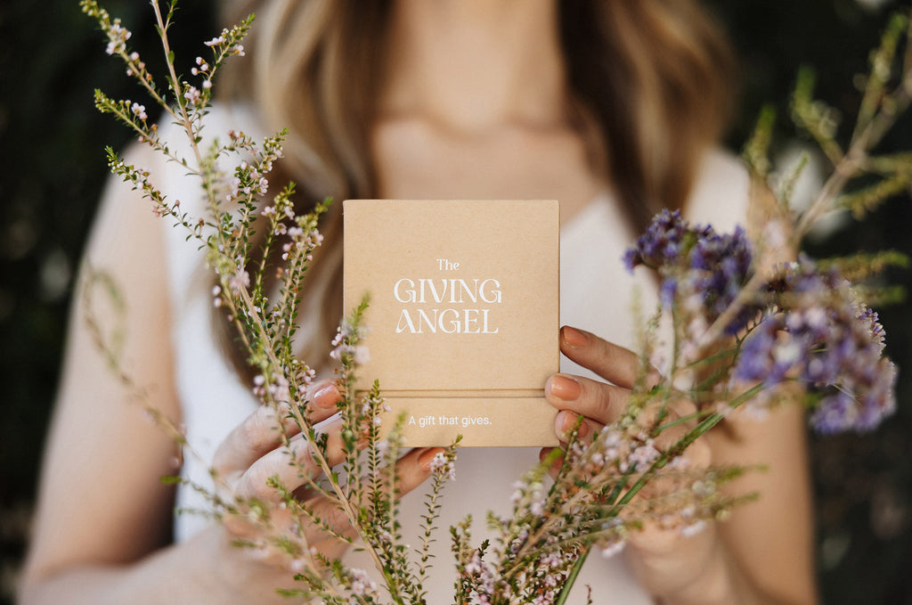 Woman holding The Giving Angel gift box surrounded by preserved flowers, a handcrafted Australian gift with a charity donation.