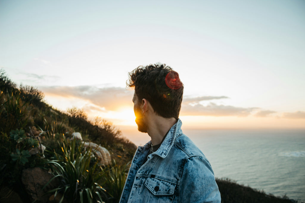 Young man looking towards the horizon, representing hope, resilience and positive mental health through The Man Cave's youth programs.